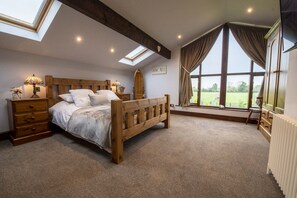 Ein Schlafzimmer mit einem hölzernen Bett, Dachfenstern, einem großen Fenster und einer Heizung.