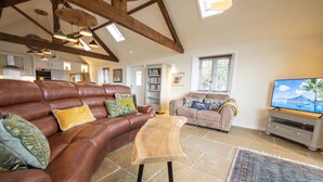 A spacious living room with a brown leather sofa, a wooden coffee table, and a television. - Lalo, Pickhill, North York Moors (Thirsk)