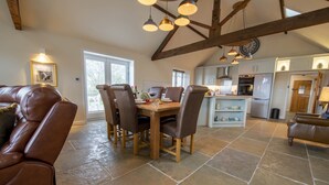 A spacious kitchen with a dining area, featuring a stone floor, wooden beams, and modern appliances. - Lalo, Pickhill, North York Moors (Thirsk)