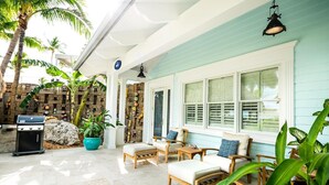 A covered outdoor seating area with wooden furniture, a grill, and potted plants. - 1 bedroom, 1 bath, full kitchen, 1 queen bed, 1 queen sleeper sofa. (Islamorada)