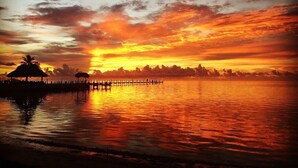 A sunset over a calm body of water with a pier and structures silhouetted against the sky. - Royal Palm North 3 Bedrooms, 3 Baths, Ocean Front, (Islamorada)