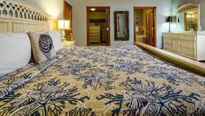 A bedroom with a large bed, a dresser, a mirror, and a door leading to a bathroom.