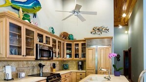 A kitchen with wooden cabinets, a central island, a ceiling fan, and a fish mural.