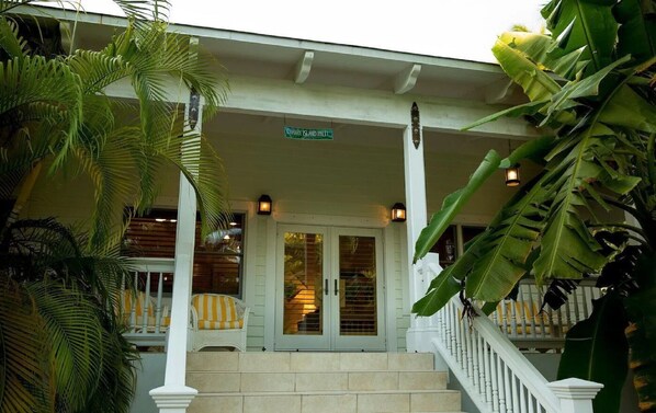 A building with a covered porch, a sign reading "CANARY ISLAND PALACE," and a staircase leading to the entrance.