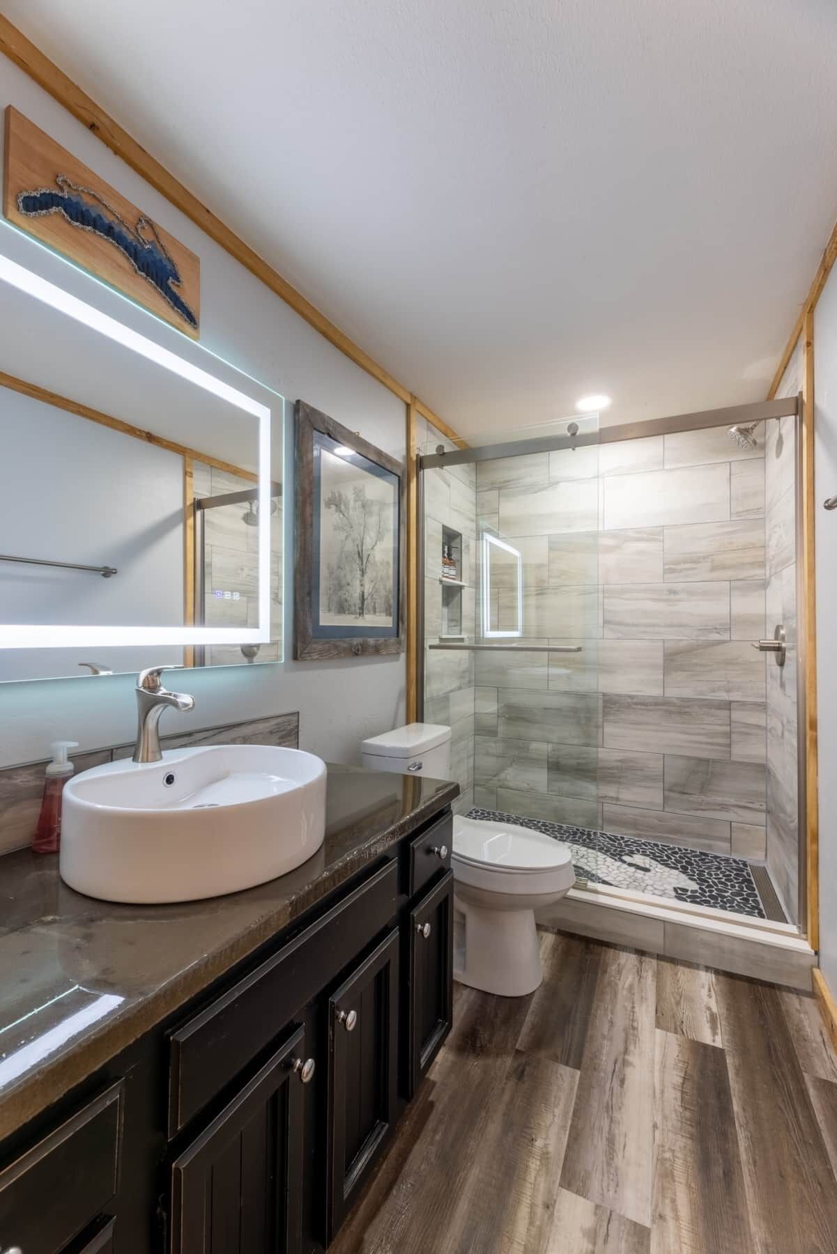 Un bagno moderno con un lavandino rotondo, un water e una cabina doccia in vetro.