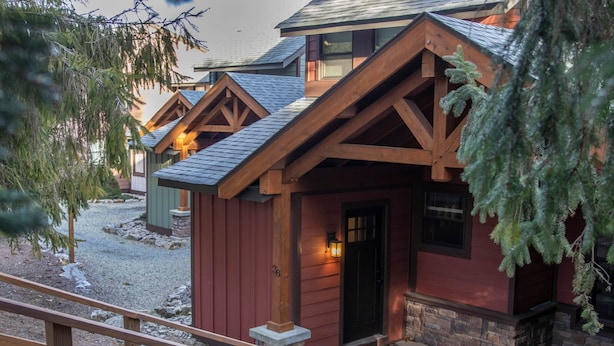 Eine rustikale Holzhütte mit Steinunterbau, Holzbalken und einer schwarzen Tür.