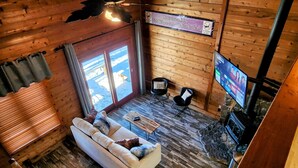 A wooden interior with a sofa, chairs, a television, and a fireplace.