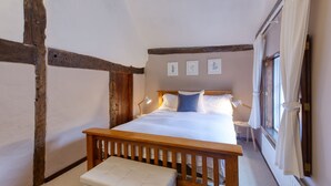 Une chambre à coucher avec un lit en bois, un banc et une fenêtre avec des rideaux.