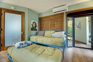 A bedroom with two beds, a wooden wardrobe, an air conditioning unit, and a door leading to a balcony. - The Brew Ridge Trail's Most Unique Home.  Sleeps 12 (Afton)