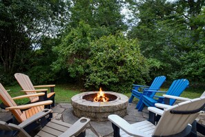 A circular fire pit surrounded by Adirondack chairs in a garden setting. - The Brew Ridge Trail's Most Unique Home.  Sleeps 12 (Afton)