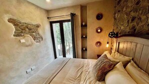 A bedroom with a large bed, a stone wall, and a window with curtains. - Incredible Loft in ValQuirico!  (Xoxtla)