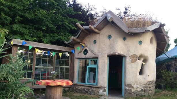 A rustic house with a unique architectural design, featuring a stone exterior and a wooden door.
