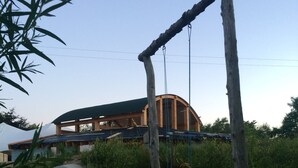A wooden swing set in a grassy area with a building in the background.