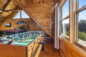 Relax in a cabin-style room with a high ceiling, exposed beams, and a foosball table for entertainment.