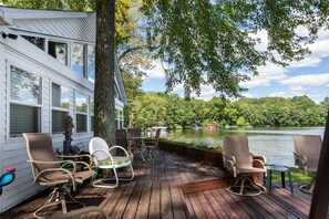 A deck with outdoor seating and a view of a lake. - Private spacious beach retreat on Wall Lake. (Delton)