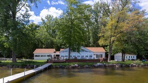 Une propriété au bord du lac, dotée d’un quai, d’une terrasse couverte et d’une maison au toit rouge.