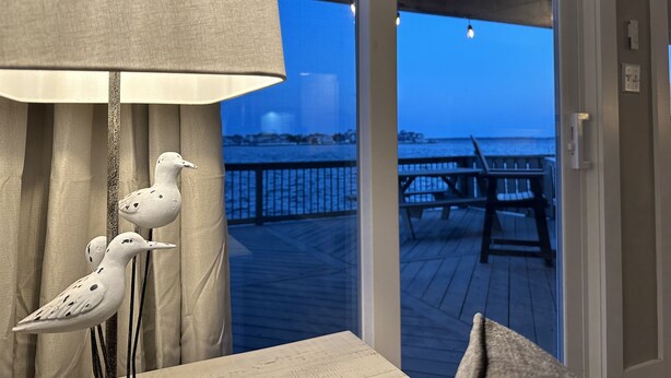 Habitación con vista a una terraza de madera y barandilla sobre un cuerpo de agua.