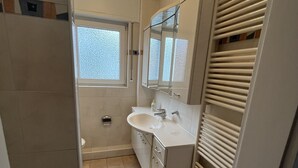 A compact bathroom with a white sink, mirror, and a window with blinds. - Oberursel old town very centrally located (Oberursel)