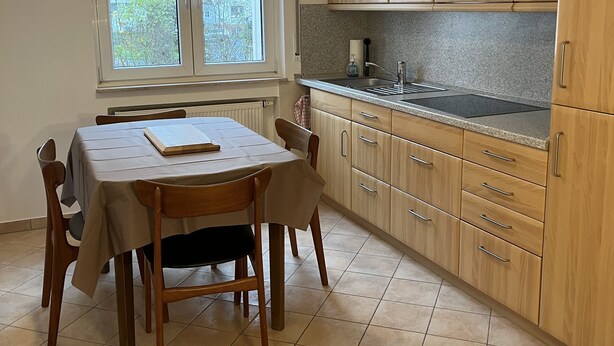 A kitchen with wooden cabinets, a dining table with chairs, a window, and a pendant light. - Oberursel old town very centrally located (Oberursel)