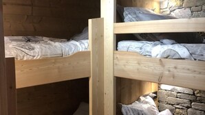 A bunk bed room with wooden beams and stone walls.