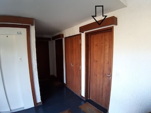 A hallway with wooden doors and a white wall.