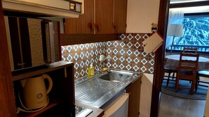 Una cuina compacta amb un rentaplat, una cafetera i un frigorífic petit.