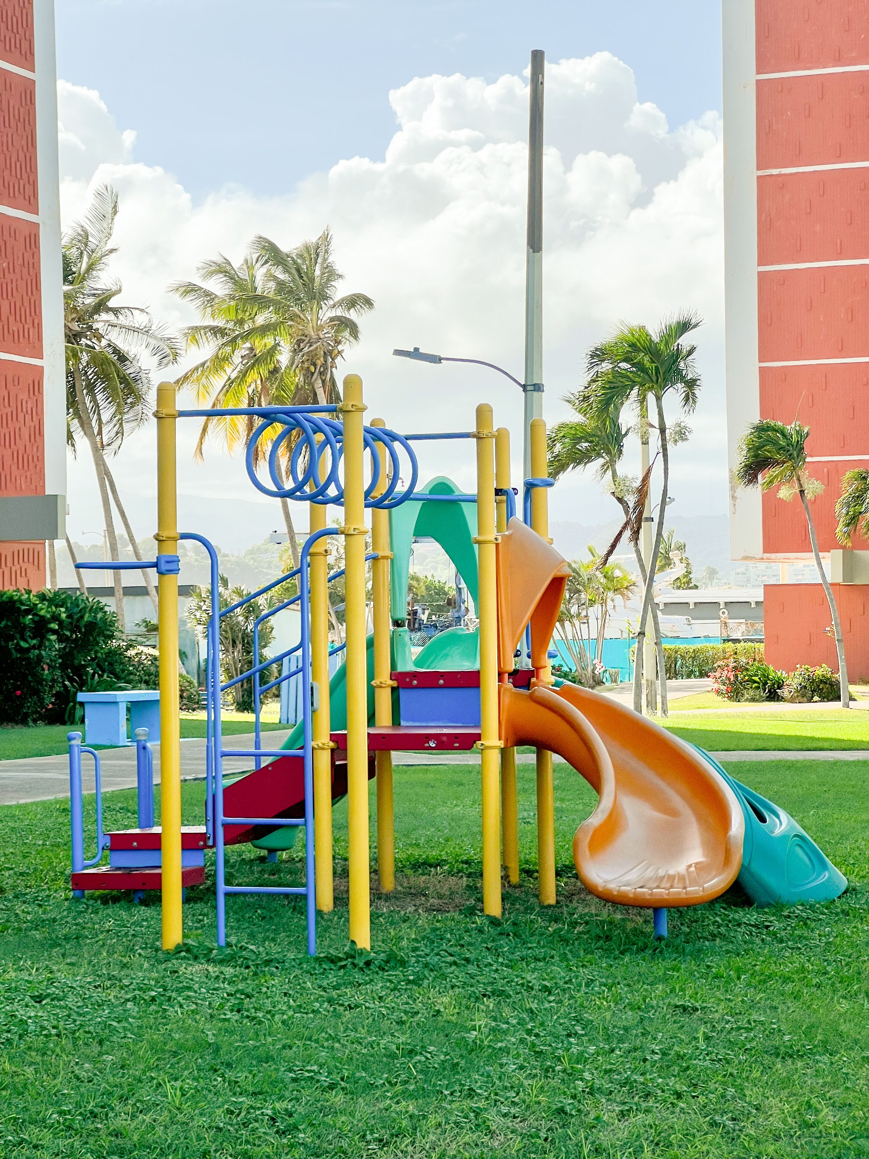 A playground with a slide, climbing structures, and a green play area.