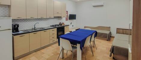 A modern kitchen with a dining area, a flat-screen TV mounted on the wall, and a built-in air conditioning unit.