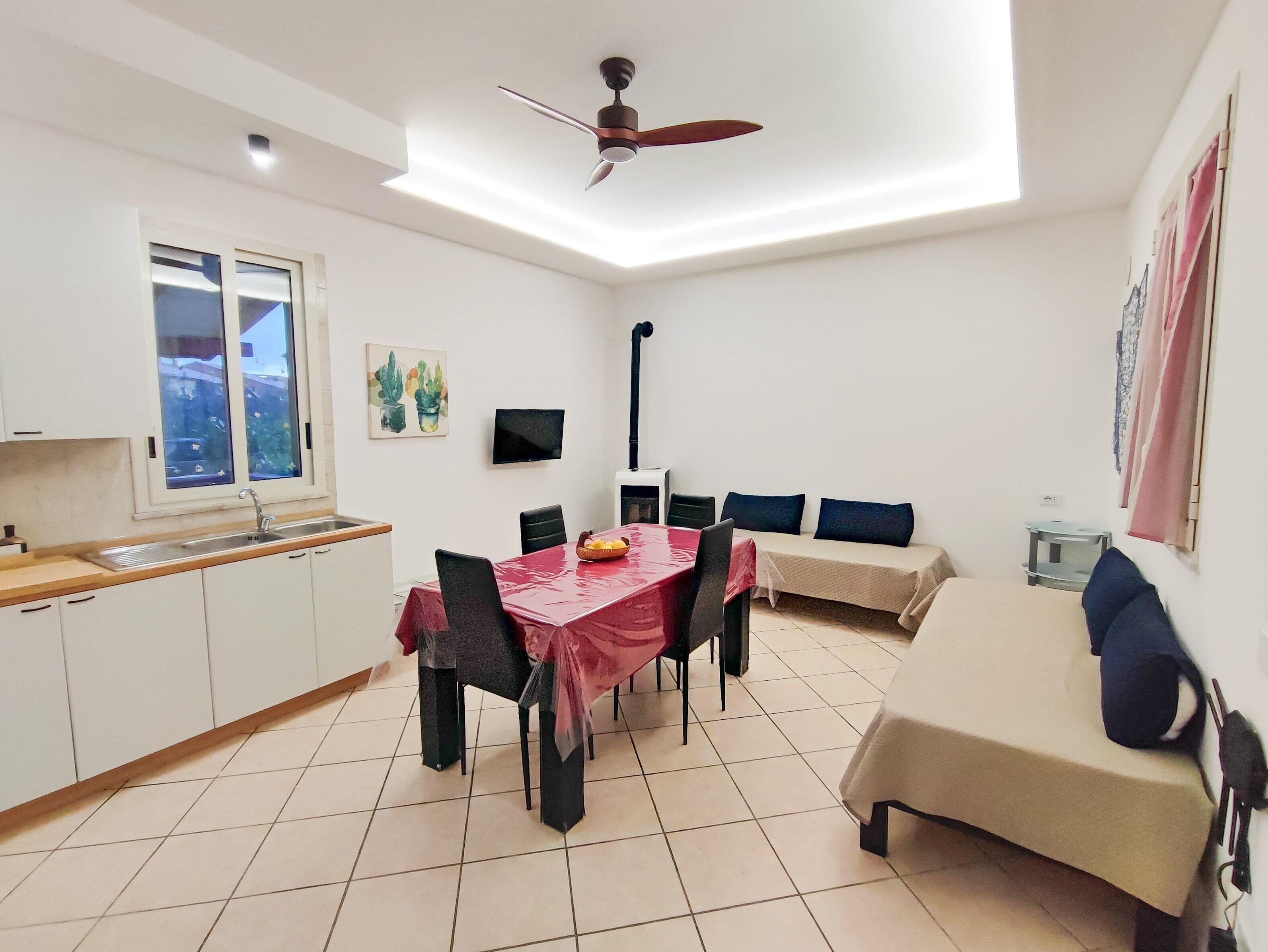 A compact kitchen with a dining area, a ceiling fan, and a TV.