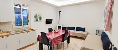 A compact kitchen with a dining area, a ceiling fan, and a TV.