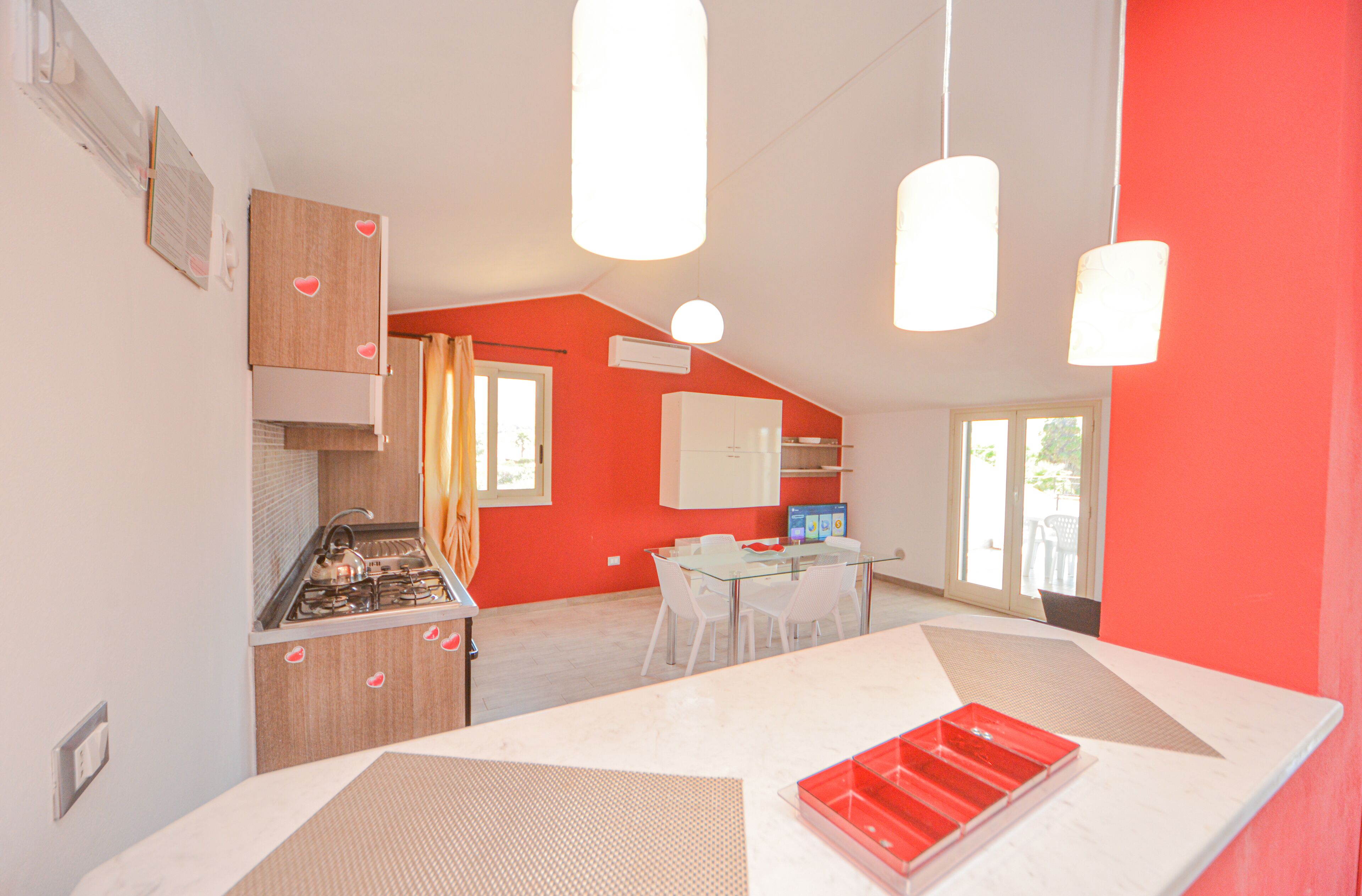 Une cuisine moderne équipée d’une cuisinière à gaz, de meubles blancs et d’un coin repas avec une table et des chaises en verre.
