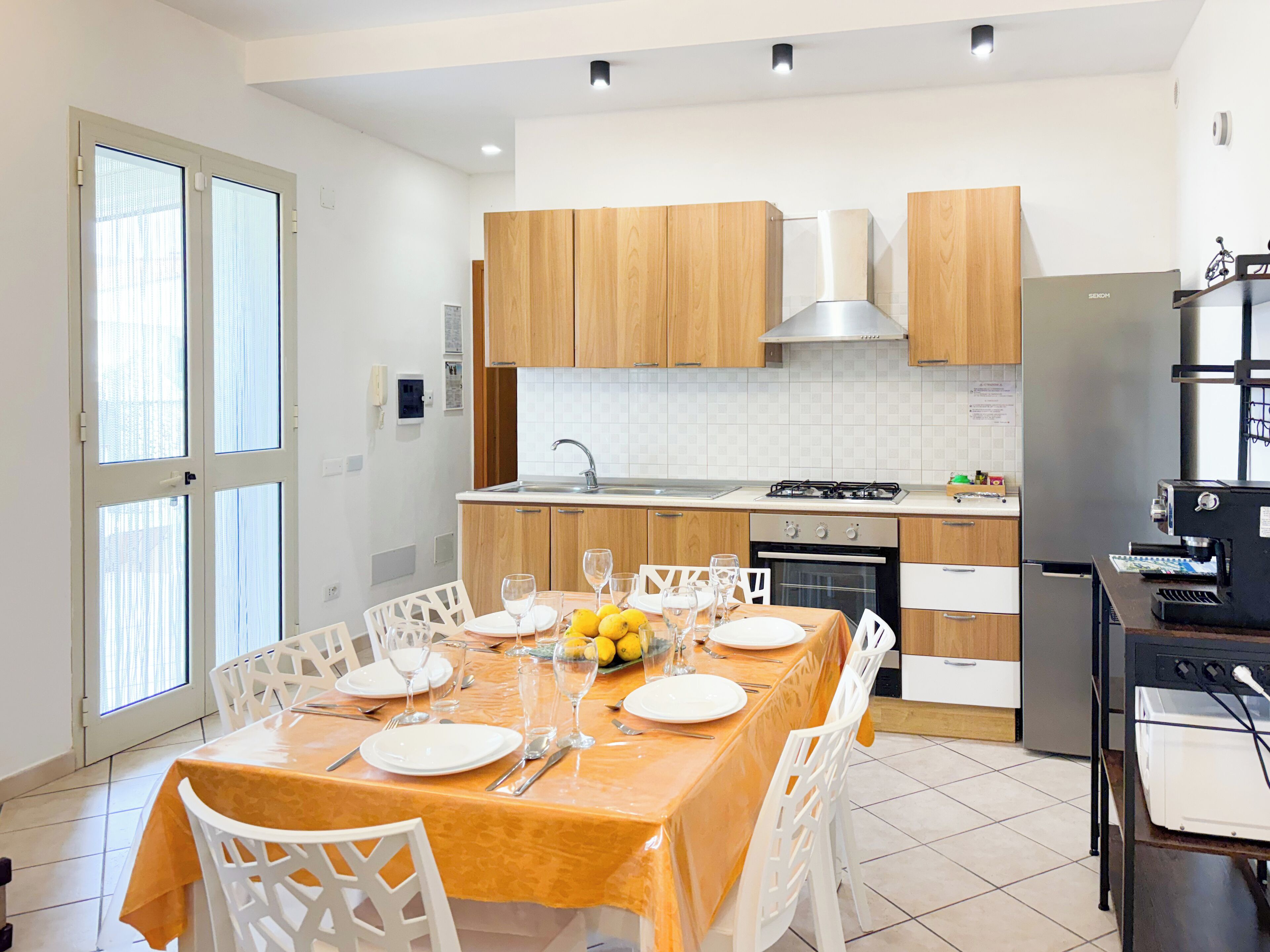 Una cocina moderna con armarios de madera, estufa de acero inoxidable y comedor con mesa dispuesta para cuatro.