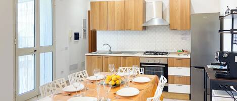 Una cocina moderna con armarios de madera, estufa de acero inoxidable y comedor con mesa dispuesta para cuatro.