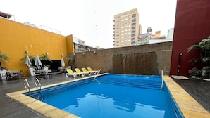 Una piscina a la terrassa amb superfície d'aigua transparent i blava, envoltada de gandules i un pont de fusta.