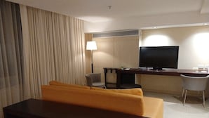 Habitació d'hotel amb un sofà, una taula petita, una televisió, una làmpada i una cadira.
