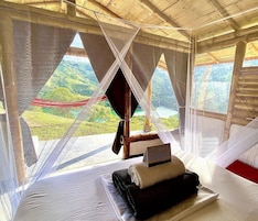 Una habitación con cama, un cartel de bienvenida y vistas a un paisaje verde a través de cortinas translúcidas.