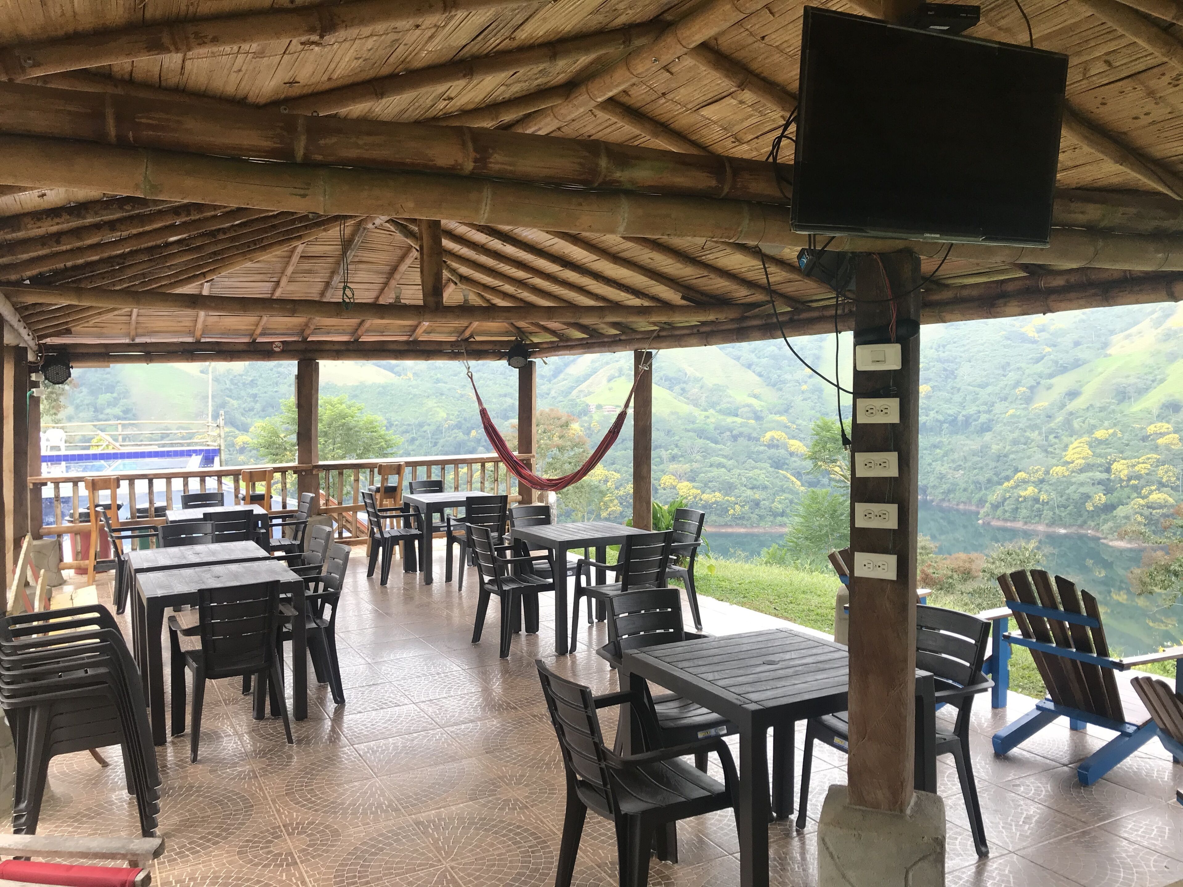 An outdoor dining area with tables and chairs, a hammock, and a view of a valley.