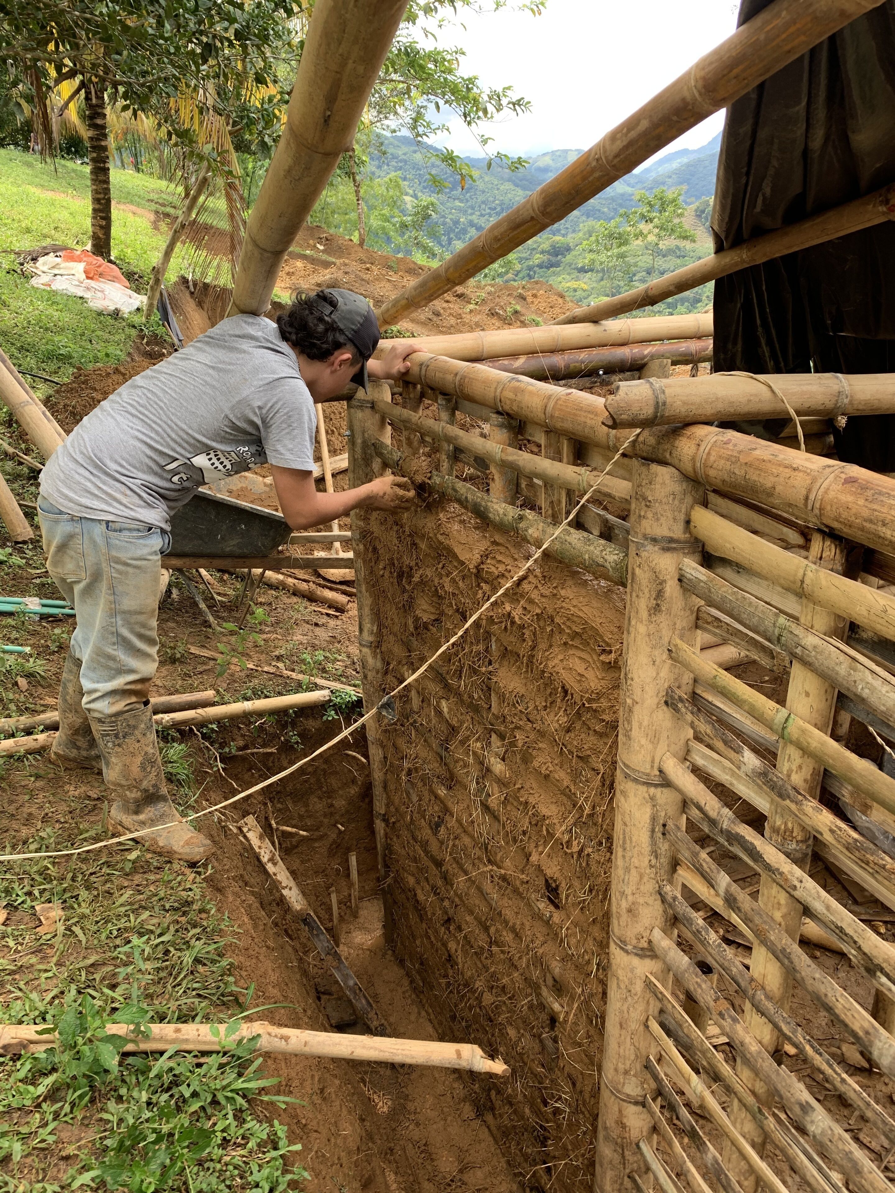 A person working on a bamboo structure in a rural setting.