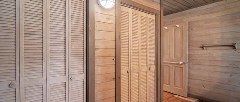 A hallway with wooden panel walls and floors, featuring a set of closed wooden doors with a light fixture above them.
