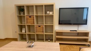 A living room with a wooden coffee table, a TV on a stand, and a shelving unit with baskets and decorative items. - Nice apartment in Candás (Candás)