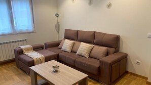 A living room with a brown sofa, a wooden coffee table, and a radiator. - Nice apartment in Candás (Candás)