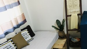 A small, neatly arranged bedroom with a single bed, a small wooden table, a ladder, and a potted plant. - 250picnics (Kigali)