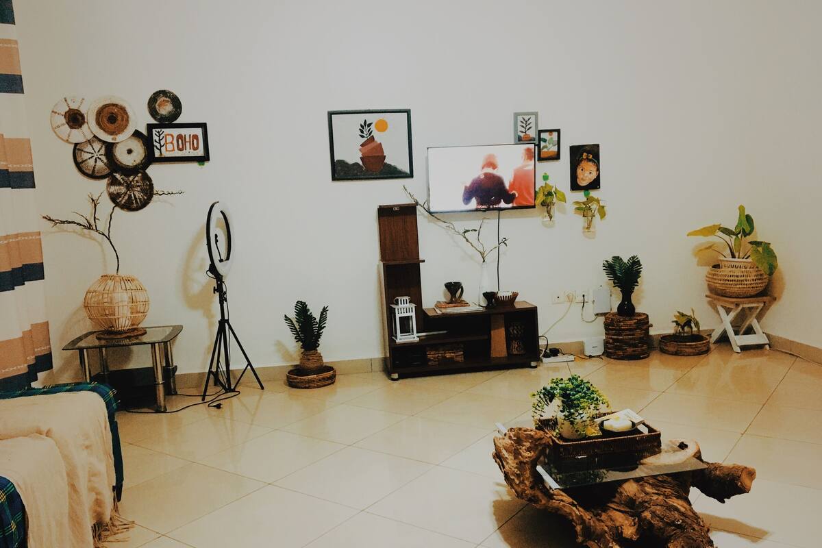 Una sala de estar con televisor, varias plantas y una mesa de centro rústica.
