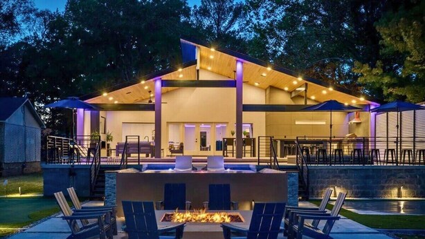 A modern outdoor patio area with a fire feature, seating, and a pool. - Lakefront Home with Pool, Game Room & Dock (Hot Springs)