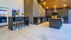 A modern kitchen with a high ceiling, built-in bar area, and a large island. - Lakefront Home with Pool, Game Room & Dock (Hot Springs)
