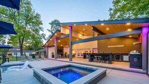 A modern outdoor pool area with a bar and seating. - Lakefront Home with Pool, Game Room & Dock (Hot Springs)