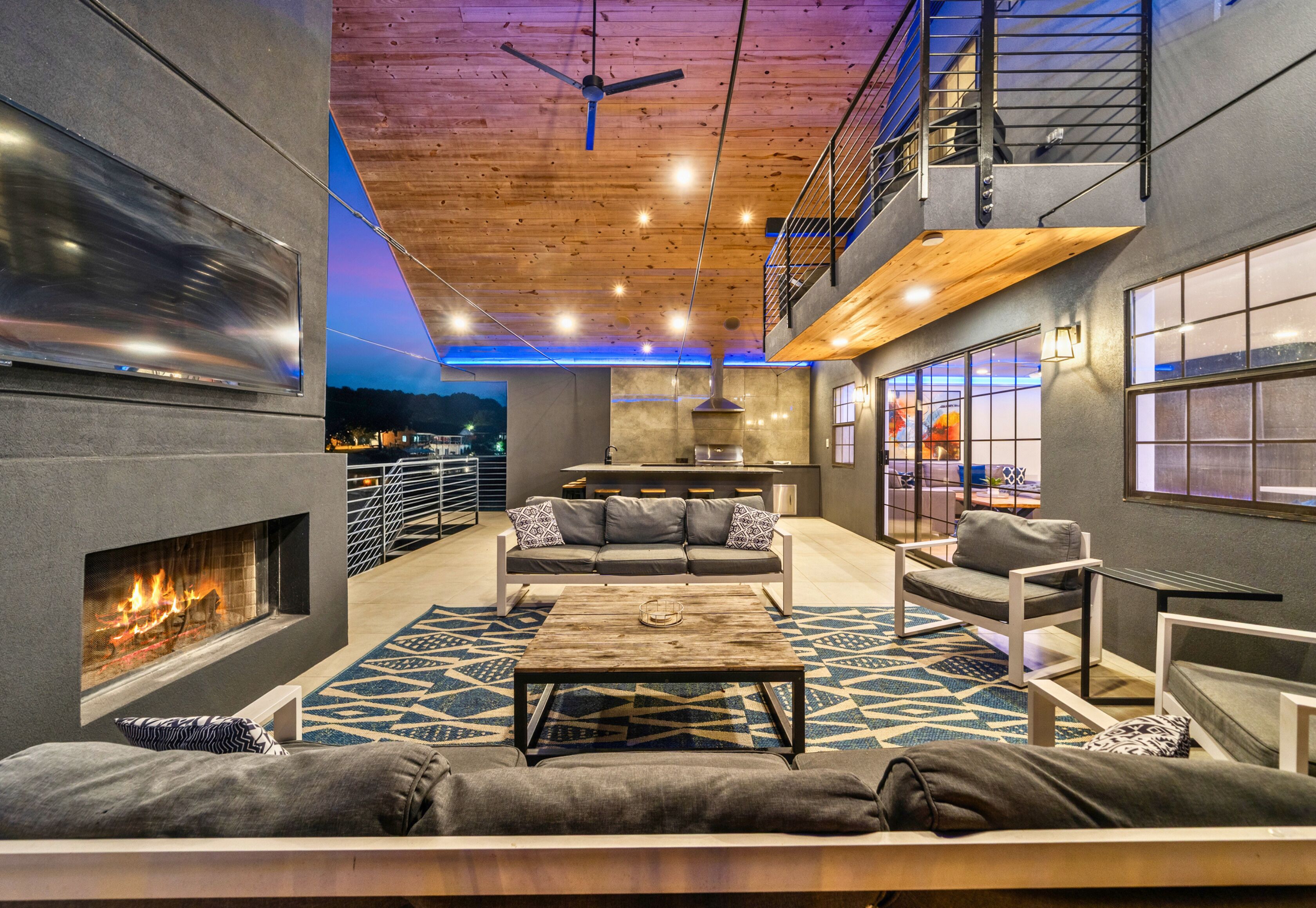 A modern interior with a fireplace, seating area, and a balcony with a view.