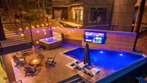 A rooftop pool area with a hot tub, lounge chairs, and a TV screen. - Lakefront Retreat w/Hot Tub, Fire Pit, Games! (Hot Springs)