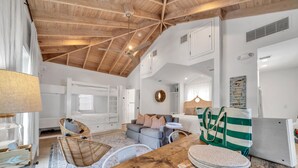 Una habitación amplia con techo de madera alto, camas literas, un sofá, una mesa de comedor y una zona de cocina.
