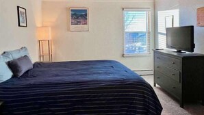 A bedroom with a bed, a dresser, a TV, a window, and a picture on the wall. - 2 BR Mountain Condo w/ views, near amazing skiing (Silverthorne)
